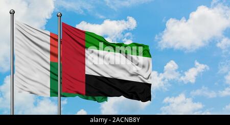 Madagascar et Emirats Arabes Unis drapeaux dans le vent contre ciel bleu nuageux blanc ensemble. Concept de diplomatie, de relations internationales. Banque D'Images