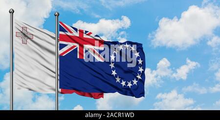 Malte et de brandir le drapeau des Îles Cook dans le vent contre ciel bleu nuageux blanc ensemble. Concept de diplomatie, de relations internationales. Banque D'Images