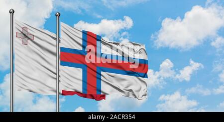 Malte et les Îles Féroé drapeaux dans le vent contre ciel bleu nuageux blanc ensemble. Concept de diplomatie, de relations internationales. Banque D'Images