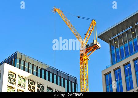 Grue jaune vif au-dessus et entre les deux blocs de bureau moderne à Machester City Centre Banque D'Images