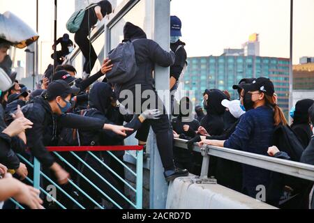 Hong Kong, Chine. 01er décembre 2019. Des milliers de manifestants pro-démocratie inscrivez-vous la marche pacifique de Tsim Sha Tsui à Hung Hom. Ici les manifestants ont grimper sur un mur de la route d'éviter la police qui poussent en avant. Banque D'Images