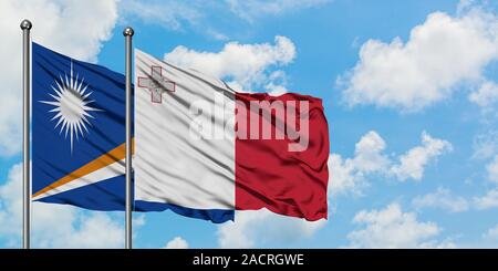 Îles Marshall et de brandir le drapeau de Malte dans le vent contre ciel bleu nuageux blanc ensemble. Concept de diplomatie, de relations internationales. Banque D'Images