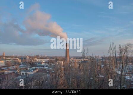 Fumée noire vient d'une cheminée, un tuyau industriel. La pollution des déchets dans l'air. Cityscape sur une soirée d'hiver Banque D'Images