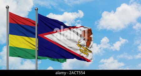 L'île Maurice et de brandir le drapeau des Samoa américaines dans le vent contre ciel bleu nuageux blanc ensemble. Concept de diplomatie, de relations internationales. Banque D'Images