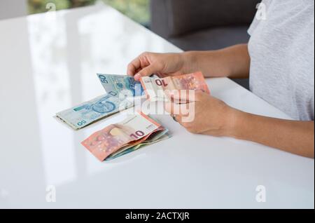 Woman holding Polski Zloty PLN et billets en mains. Euro argent et Polski Zloty PLN dans une main de femme sur un fond blanc. Euro en Pologne. Banque D'Images
