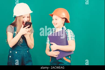 La fête du travail. 1 mai. Projet d'école. Inspecteur de contremaître. La réparation. Les petits enfants en casque avec tablette. petites filles réparer ensemble en atelier. crier sur travailleur dans l'appel téléphonique. discuter de problèmes. Banque D'Images