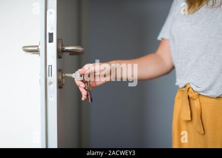 Femme mains l'ouverture d'une porte avec les touches. Close up. Serrure à clé déverrouille la porte. Pour en revenir à la maison. Banque D'Images