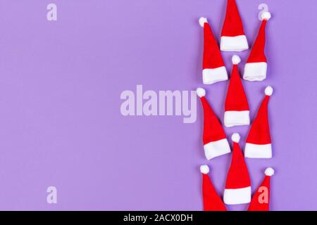Vue de dessus od rouge élégant Santa hats sur fond coloré. Joyeux Noël concept avec copie espace. Banque D'Images