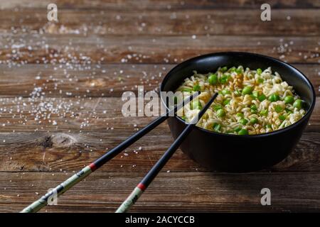 Bol de nouilles avec les pois frais et l'oignon haché. Banque D'Images