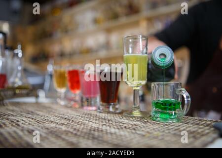 Barman verse divers d'alcool boire dans de petits verres sur bar Banque D'Images