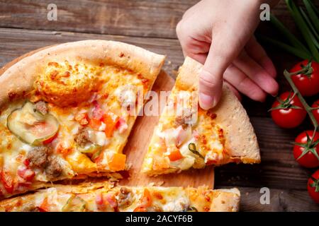 Cueillette à la main Tranche de pizza savoureuse allongé sur table en bois Banque D'Images