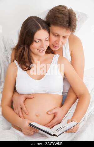 Femme enceinte et son mari reading book Banque D'Images