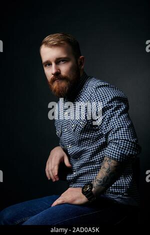 Homme barbu rouge réfléchie studio portrait sur fond sombre Banque D'Images