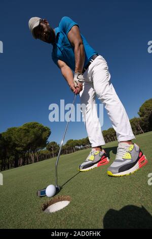 Joueur de golf frappant tiré sur journée ensoleillée, objectif grand angle Banque D'Images