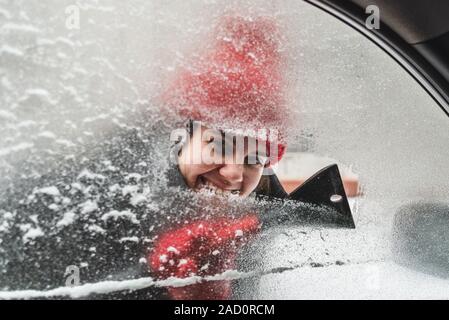 Jeune Jolie femme voiture nettoyage après la tempête de neige Banque D'Images