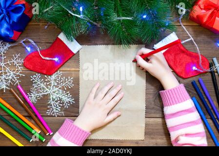 Les enfants lettre au Père Noël. Petite fille écrit une lettre avec des feutres de couleur sur une table en bois avec des décorations de Noël sur l'ancien Banque D'Images