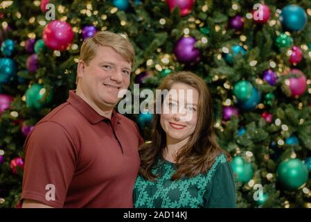 Couple devant un arbre de Noël décoré Banque D'Images