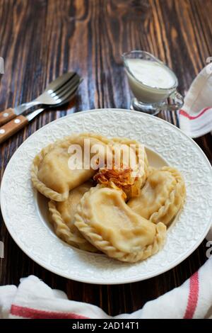 Vareniki Varenyky ou pyrohy, quenelles, pâtisserie traditionnelle orientale avec des pommes de terre farcies plat servi avec de la crème et oignons caramélisés Banque D'Images