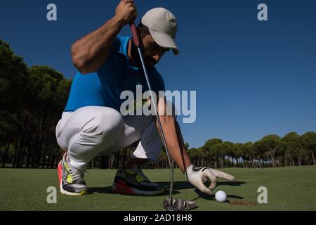 La main de l'homme mettre dans le trou de balle de golf Banque D'Images