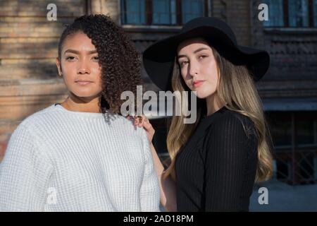 Une paire de belles filles mexicaines debout contre la toile d'un vieux bâtiment universitaire. Deux soeurs. Les jeunes filles. Prise de vue de la mode. G Banque D'Images