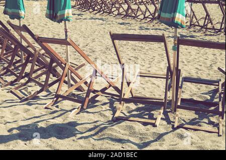 Transats et parasols pliés vintage on sandy beach Banque D'Images