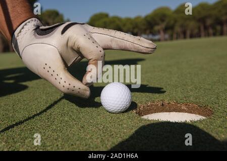 La main de l'homme mettre dans le trou de balle de golf Banque D'Images