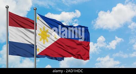 Pays-bas et Philippines drapeaux dans le vent contre ciel bleu nuageux blanc ensemble. Concept de diplomatie, de relations internationales. Banque D'Images