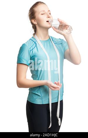 Beau Modèle de remise en forme féminine tenant une bouteille d'eau, portant un ruban à mesurer Banque D'Images