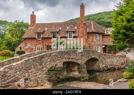 Caché, non loin du village de Porlock dans le Somerset rural, un pont traverse un ruisseau menant à un chalet pittoresque et de bois au-delà. Banque D'Images