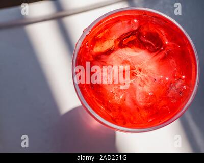 Avec un beau verre à cocktail rose et des cubes de glace, debout sur un tableau blanc contre l'ombre de feuilles de palmier. Vue de dessus, close-up. Le concept de Banque D'Images