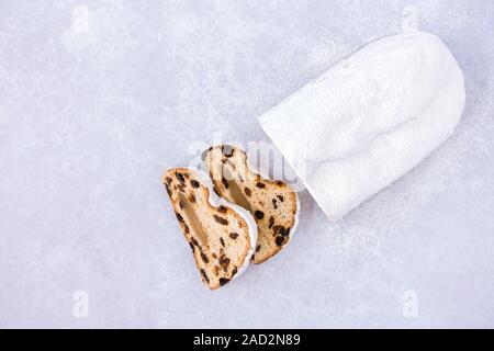 Des stollen allemand, christstollen avec amandes coupées en tranches sur fond violet-bleu pastel de sucre glace et beaucoup de copier l'espace. Vue d'en haut. Banque D'Images