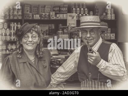 Couple heureux, robe des années 1940, réagissant à l'époque des années 1940 épicerie ancienne, événement de la seconde Guerre mondiale du chemin de fer de Severn Valley; photo en noir et blanc avec vignette. Banque D'Images