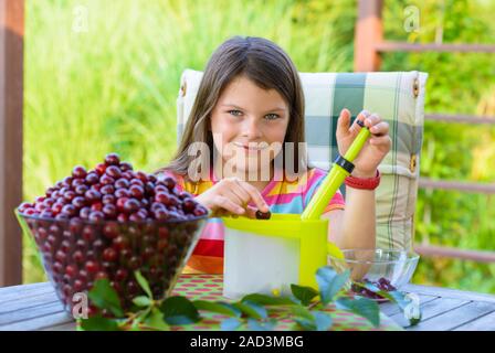 Lapidation de cerises fraîches par jeune jolie fille Banque D'Images