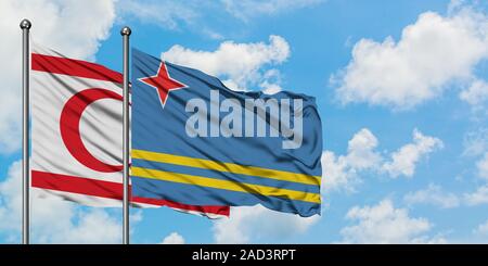 Le nord de Chypre et de brandir le drapeau d'Aruba dans le vent contre ciel bleu nuageux blanc ensemble. Concept de diplomatie, de relations internationales. Banque D'Images