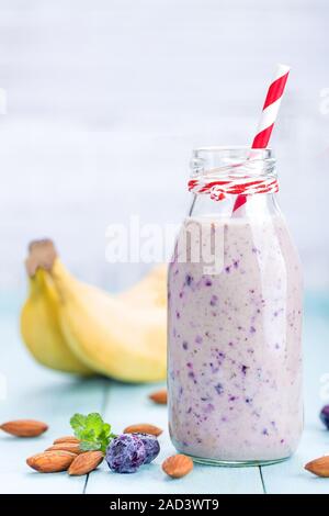 Régime de bananes et de myrtilles avec du yogourt ou smoothie lait, d'amandes et de baies fraîches dans des bouteilles en verre, des aliments sains Banque D'Images
