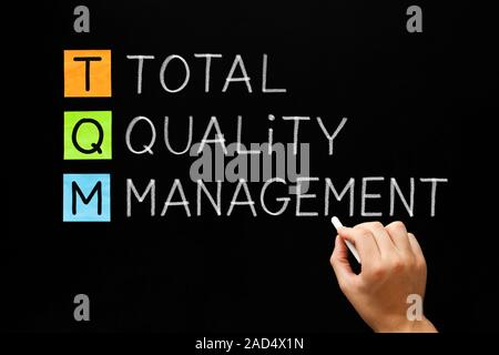 La main de l'acronyme TQM Total Quality Management concept avec craie blanche sur tableau noir. Banque D'Images