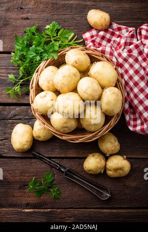 Pommes de terre crues dans le panier sur la table en bois, vue du dessus Banque D'Images