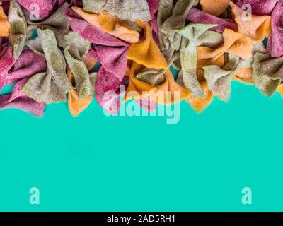 Pile de couleur Tri séchées italiennes pâtes farfalle. Différentes couleurs de nœud papillon sur fond couleur menthe verte à la mode Banque D'Images