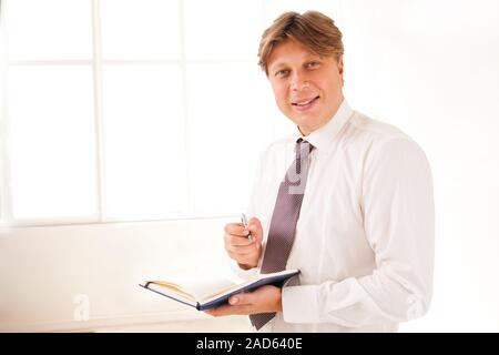 Smiling Businessman in office holding diary Banque D'Images