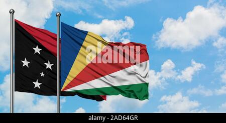 La Papouasie-Nouvelle-Guinée et de brandir le drapeau des Seychelles dans le vent contre ciel bleu nuageux blanc ensemble. Concept de diplomatie, de relations internationales. Banque D'Images