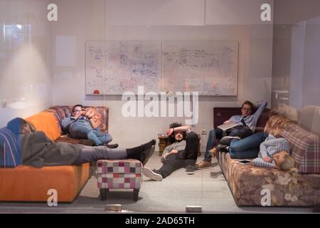 Les développeurs de logiciels de dormir sur un canapé dans la salle de bureau démarrage créative Banque D'Images