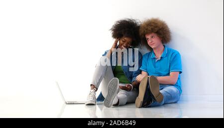 Couple multiethnique assis sur le plancher à l'aide d'un ordinateur portable et tablette Banque D'Images