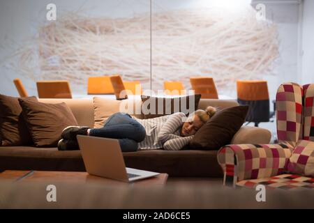 Femme dormir sur un canapé dans un bureau de création Banque D'Images