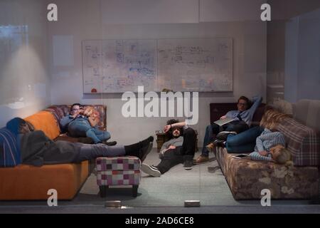 Les développeurs de logiciels de dormir sur un canapé dans la salle de bureau démarrage créative Banque D'Images