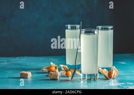 Cocktail sans alcool avec l'Ouzo anis grec brandy ou de boire de l'alcool en arabe dans grand verre de Raki, décorées Physalis peruviana et le sucre brun sur bleu c Banque D'Images