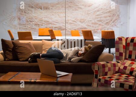 Femme dormir sur un canapé dans un bureau de création Banque D'Images