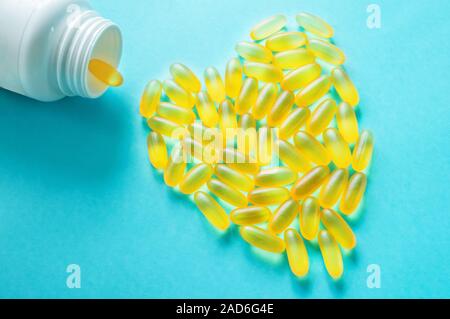 Grand medical capsules et comprimés-vitamines et les additifs alimentaires sur fond bleu sont en forme de cœur. Copier l'espace. Close up. Selective focus Banque D'Images