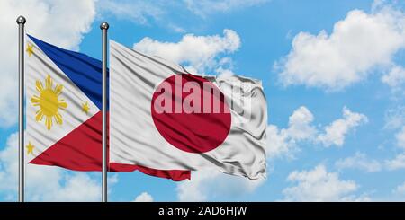 Les Philippines et le Japon drapeaux dans le vent contre ciel bleu nuageux blanc ensemble. Concept de diplomatie, de relations internationales. Banque D'Images