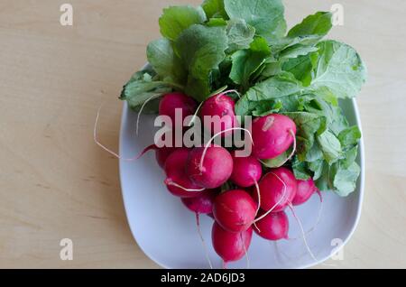 Radis rouge sur une plaque sur une table en bois. Banque D'Images