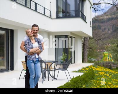 Couple hugging in front of new luxury home Banque D'Images